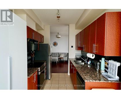 A kitchen with brown cabinets and a black refrigerator.