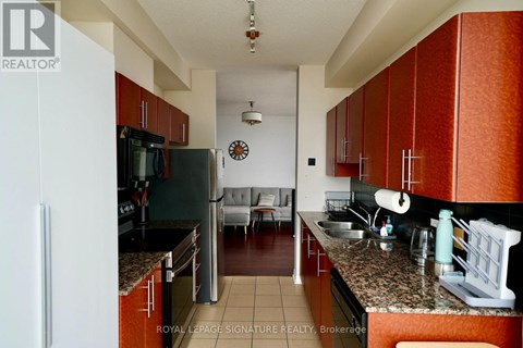 A kitchen with brown cabinets and a black refrigerator.
