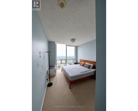 A bedroom with a large bed and a window overlooking the city.