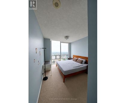 A bedroom with a large bed and a window overlooking the city.