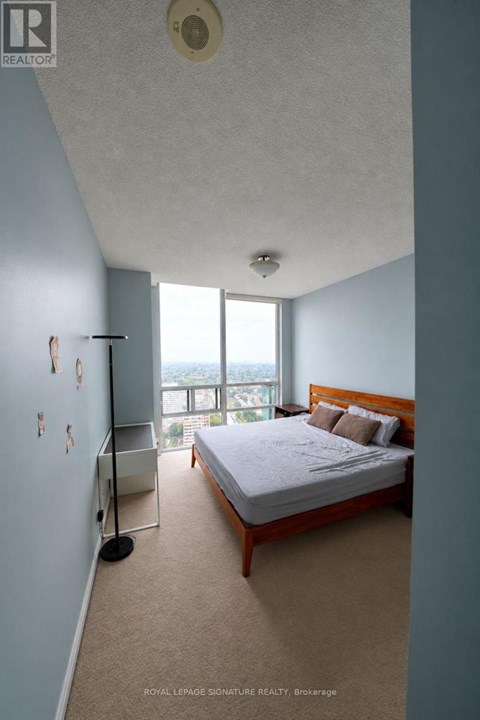 A bedroom with a large bed and a window overlooking the city.