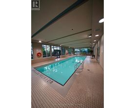 A large indoor swimming pool with a tiled floor and walls.