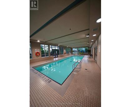 A large indoor swimming pool with a tiled floor and walls.