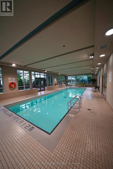 A large indoor swimming pool with a tiled floor and walls.
