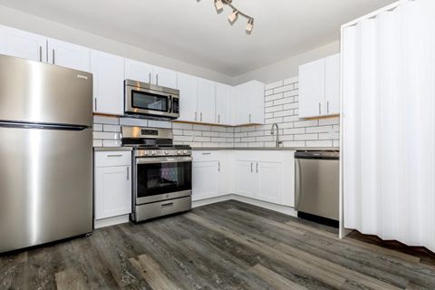 A kitchen with white cabinets and a stainless steel refrigerator.