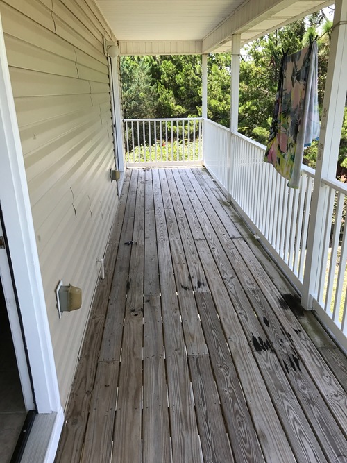 A wooden deck with a white railing and a door.