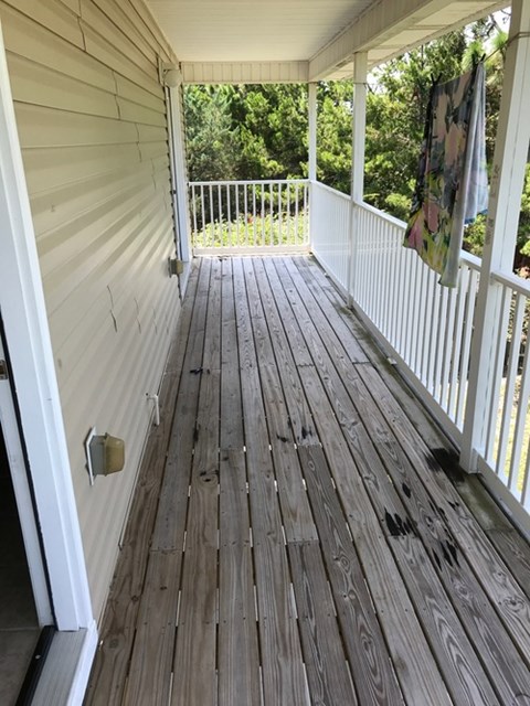 A wooden deck with a white railing and a door.