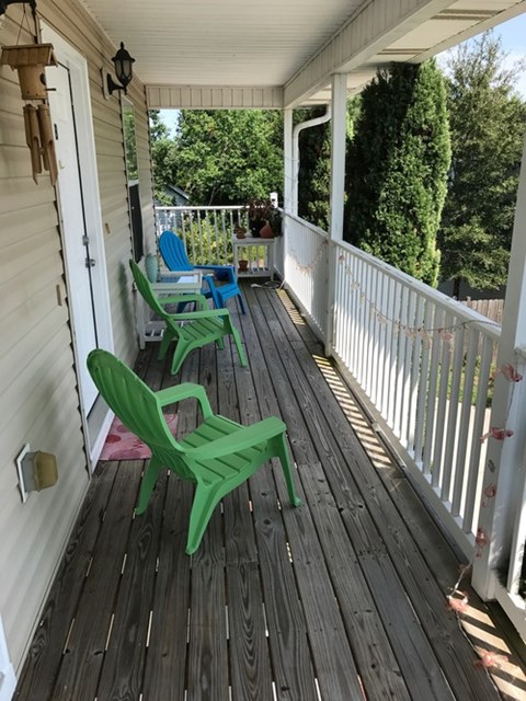 A wooden deck with two green chairs and a white railing.