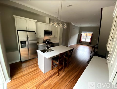 A kitchen with a white island and wooden floors.