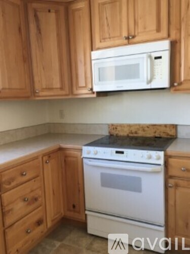 A kitchen with wooden cabinets and a white microwave above the stove.