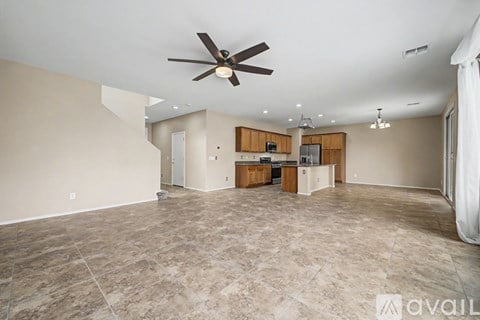 A spacious living room with a ceiling fan and tiled flooring.