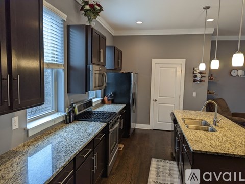 A kitchen with granite countertops and dark brown cabinets.