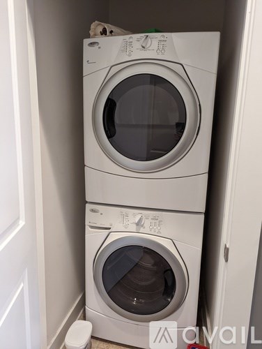 Two white washing machines stacked on top of each other in a small space.