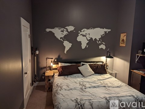 A bedroom with a world map on the wall and a bed with a floral patterned bedspread.