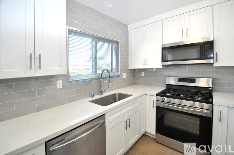 A kitchen with white cabinets and a stainless steel dishwasher and oven.