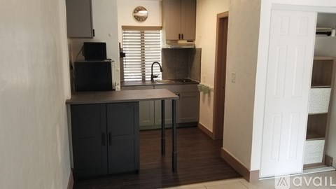A kitchen with black cabinets and a white door.