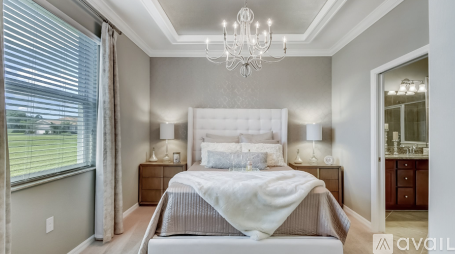 A bedroom with a large bed and a chandelier.