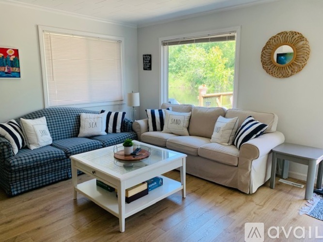 A living room with a sofa, a coffee table, and a window with blinds.