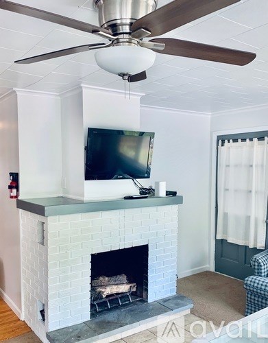 A living room with a fireplace and a television mounted above it.