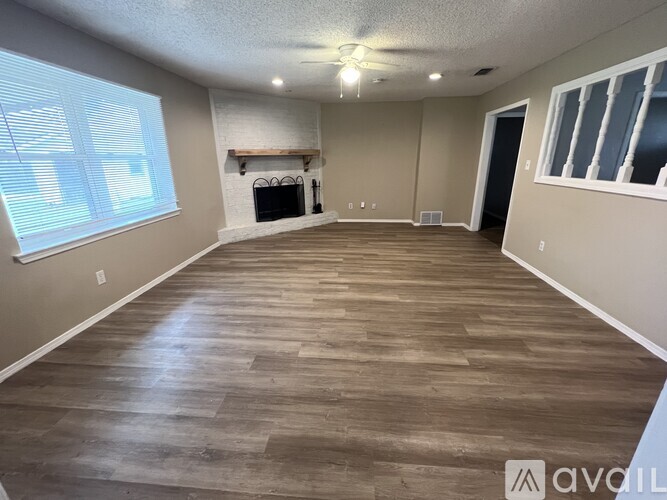 A spacious room with wooden flooring and a fireplace.
