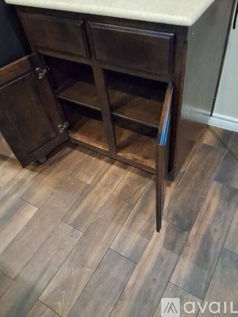 A kitchen island with a white countertop and a wooden cabinet with a pull out drawer.