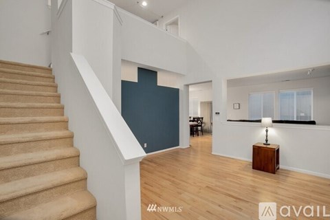 A staircase with a beige carpeted runner leads up to a landing with a dark blue wall and a window with blinds.