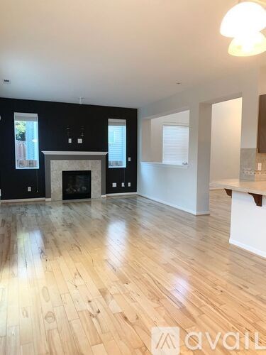 A spacious room with a fireplace and wooden flooring.