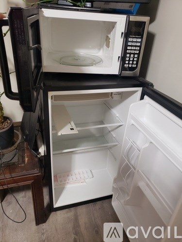 A white microwave oven is on top of a white refrigerator.