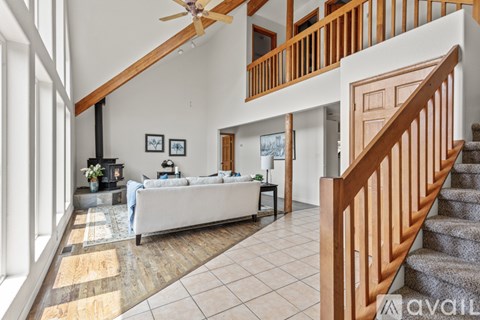 A living room with a couch, a fireplace, and a staircase.