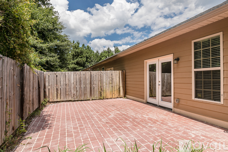 A house with a brown fence and a red brick walkway.