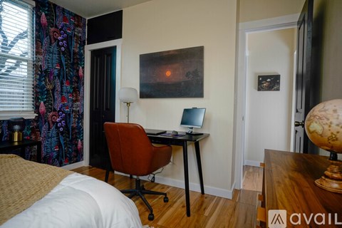 A room with a desk, chair, and a painting on the wall.