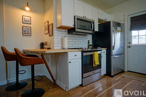 A kitchen with a black refrigerator and white cabinets.