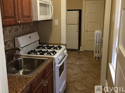 A kitchen with a stove, sink, and refrigerator.