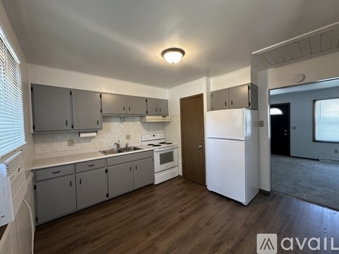 A kitchen with white appliances and wooden floors.