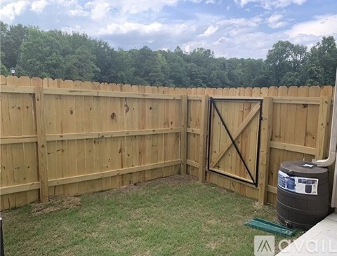 A wooden fence with a gate and a trash can in the yard.