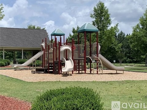 A playground with a red and white slide and a green roofed structure.