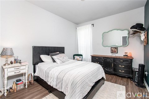 A bedroom with a bed, nightstand, and a mirror on the wall.
