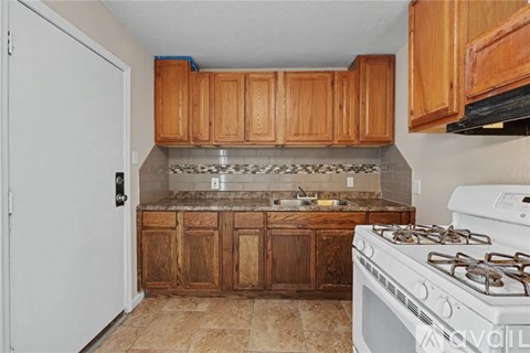 A kitchen with a white stove and wooden cabinets.