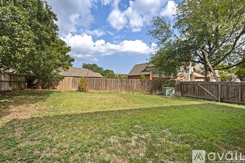A backyard with a fence and trees.