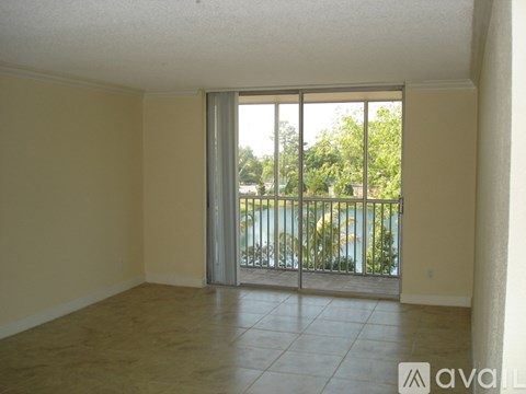 A room with a sliding glass door leading to a balcony with a view of a pool and trees.