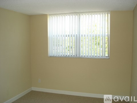 A room with a window covered by white blinds.