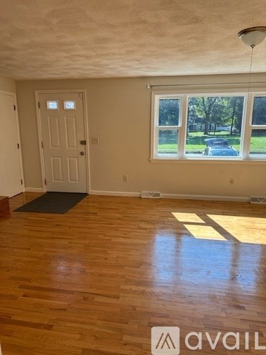 A room with wooden floors and a door leading to a backyard.