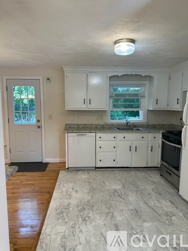 A kitchen with white cabinets and a wooden floor.