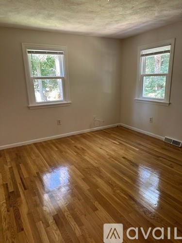 A room with wooden floors and two windows.