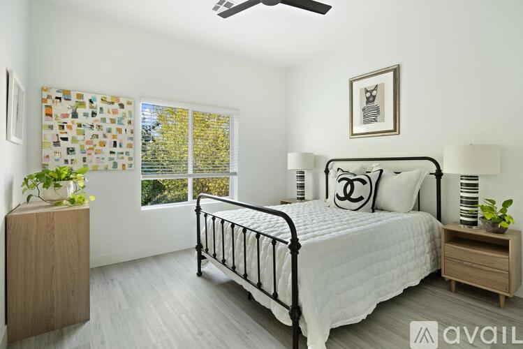A bedroom with a bed, nightstand, and window with blinds.