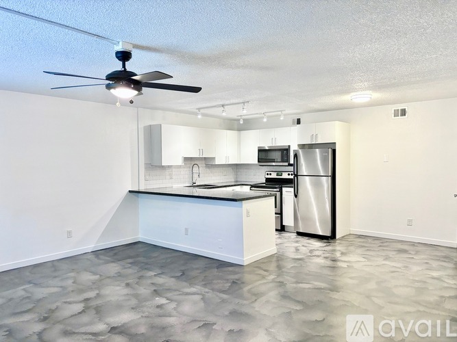 A kitchen with a fan and a refrigerator.