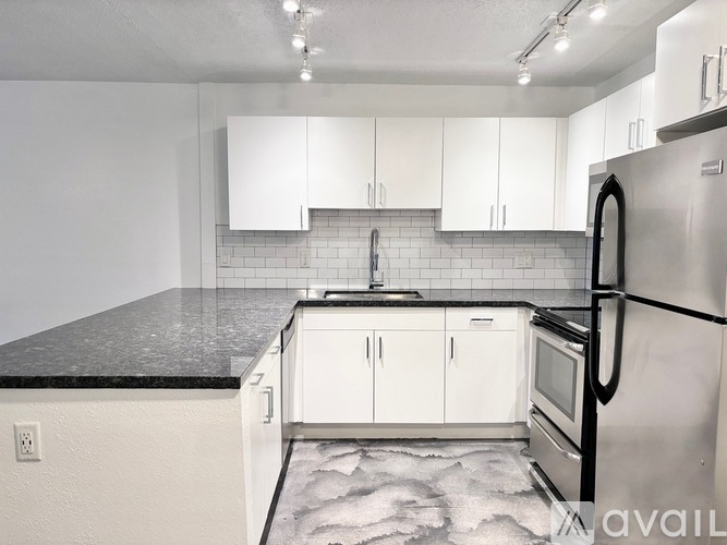 A kitchen with white cabinets and a black fridge.