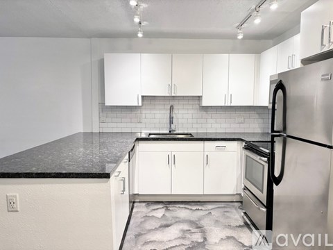 A kitchen with white cabinets and a black fridge.