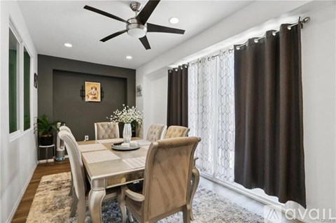 A dining room with a table set for two and a ceiling fan.