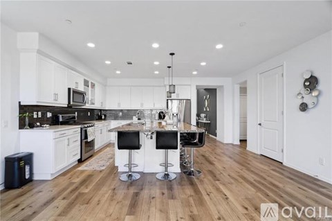 A modern kitchen with white cabinets and a wooden floor.
